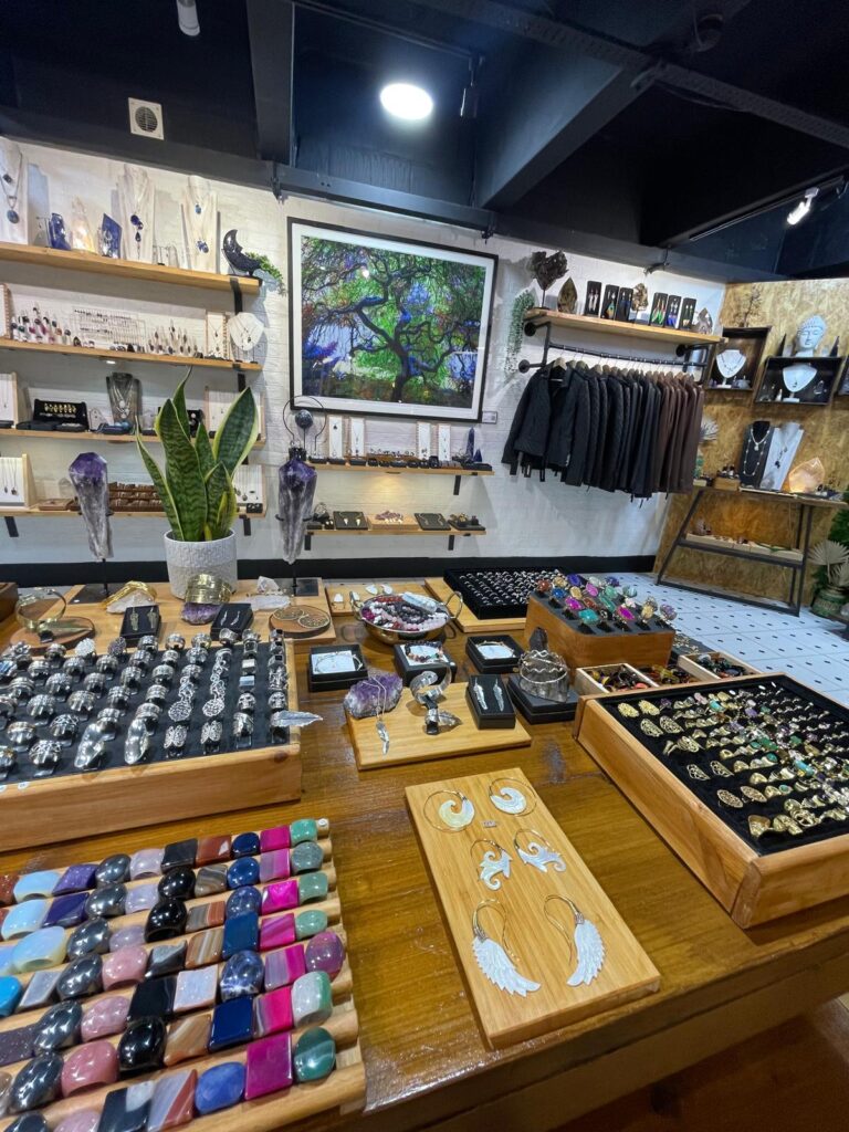 The counter inside the High Barnet shop: silver rings, tumbled stones, earrings on wooden boards and the tree painting behind